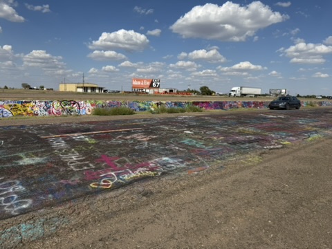 Cadillac Ranch beside a Route 66 sign under a blue sky