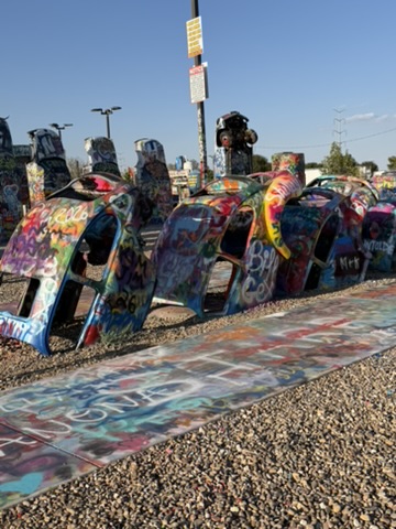 A row of painted Volkswagen Beetles buried at Slug Bug Ranch